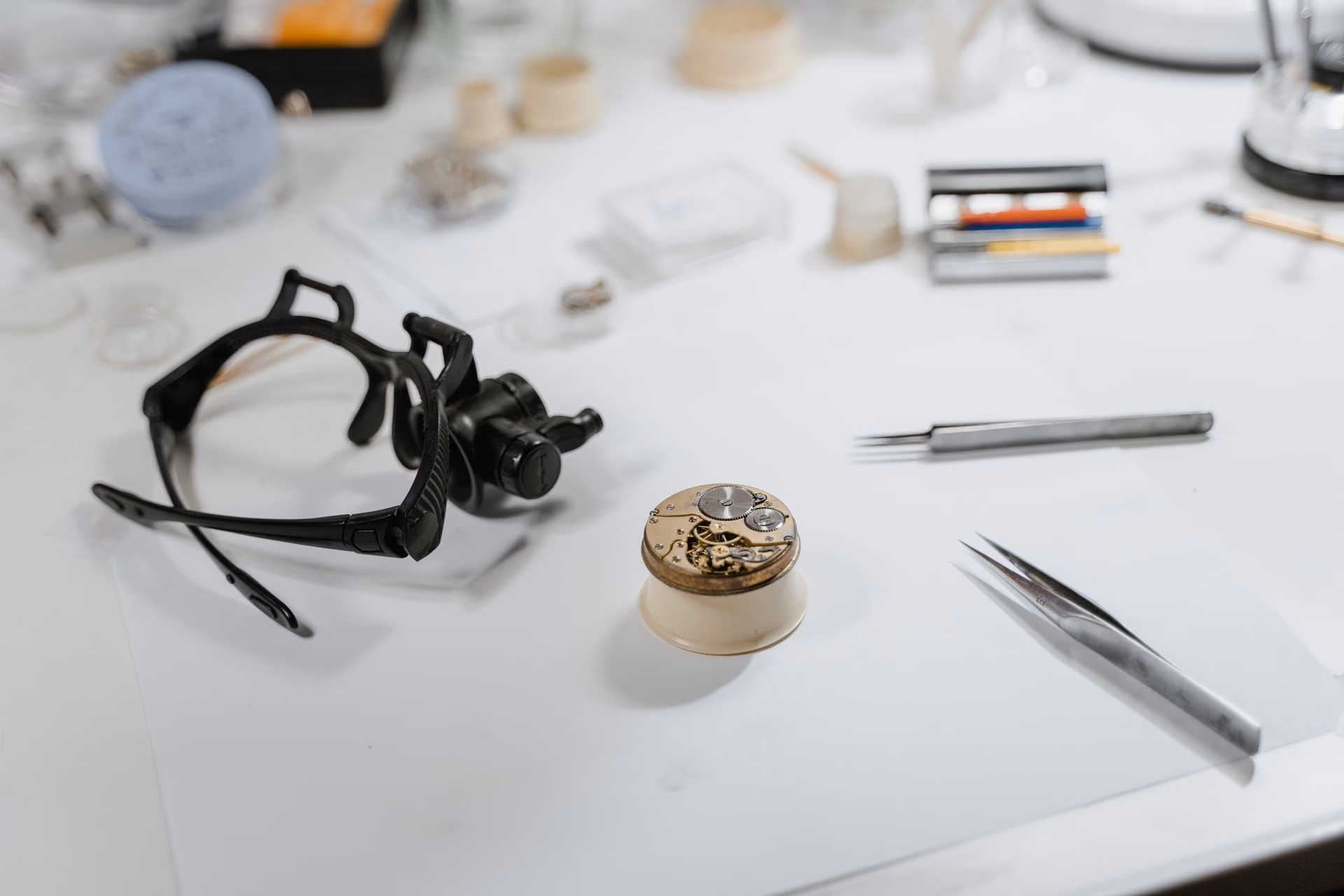 Un atelier de lutherie éclairé à la lampe : au mur, un râtelier de rabots et de ciseaux à bois ; sur l'établi, une caisse de guitare en cours de montage et un ordinateur portable ouvert ; au premier plan, une pièce de bois découpée posée sur une scie à table.
